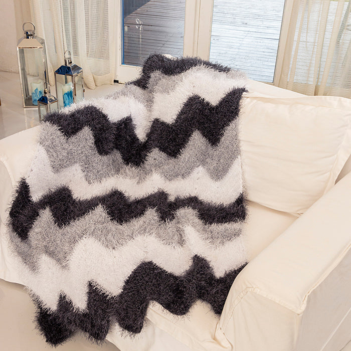 Circulo Natural Luxury Decor - Fluffy Yarn, 180 m / 280 g - Zigzag patterned throw blanket on a white couch with a window in the background