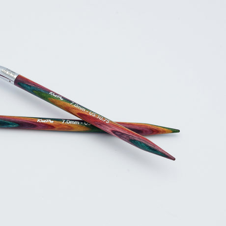 KnitPro Symfonie 2 fixed circular knitting needles with swivel cable, 60 cm - Two wooden knitting needles with a colorful, marbled pattern of red, green, and orange, crossed on a plain white background. The brand name 'Kreft' is printed in white on the shafts.